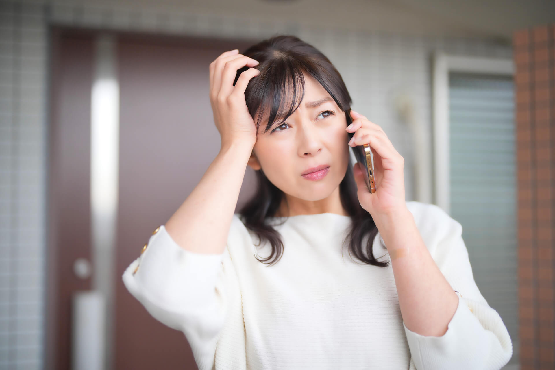 電話を持って困惑する女性
